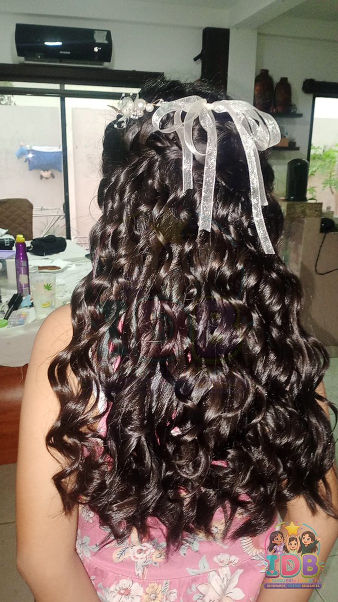 Niña de espaldas con rizos definidos y lazo blanco