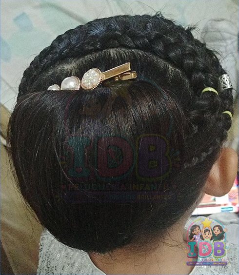 Recogido trenzado con broche de perlas en una niña